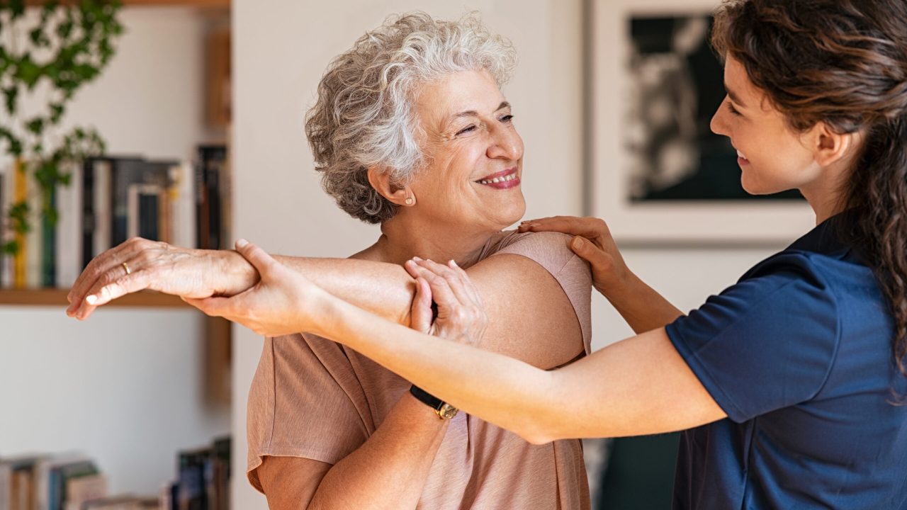 Senior woman with trainer exercising at home